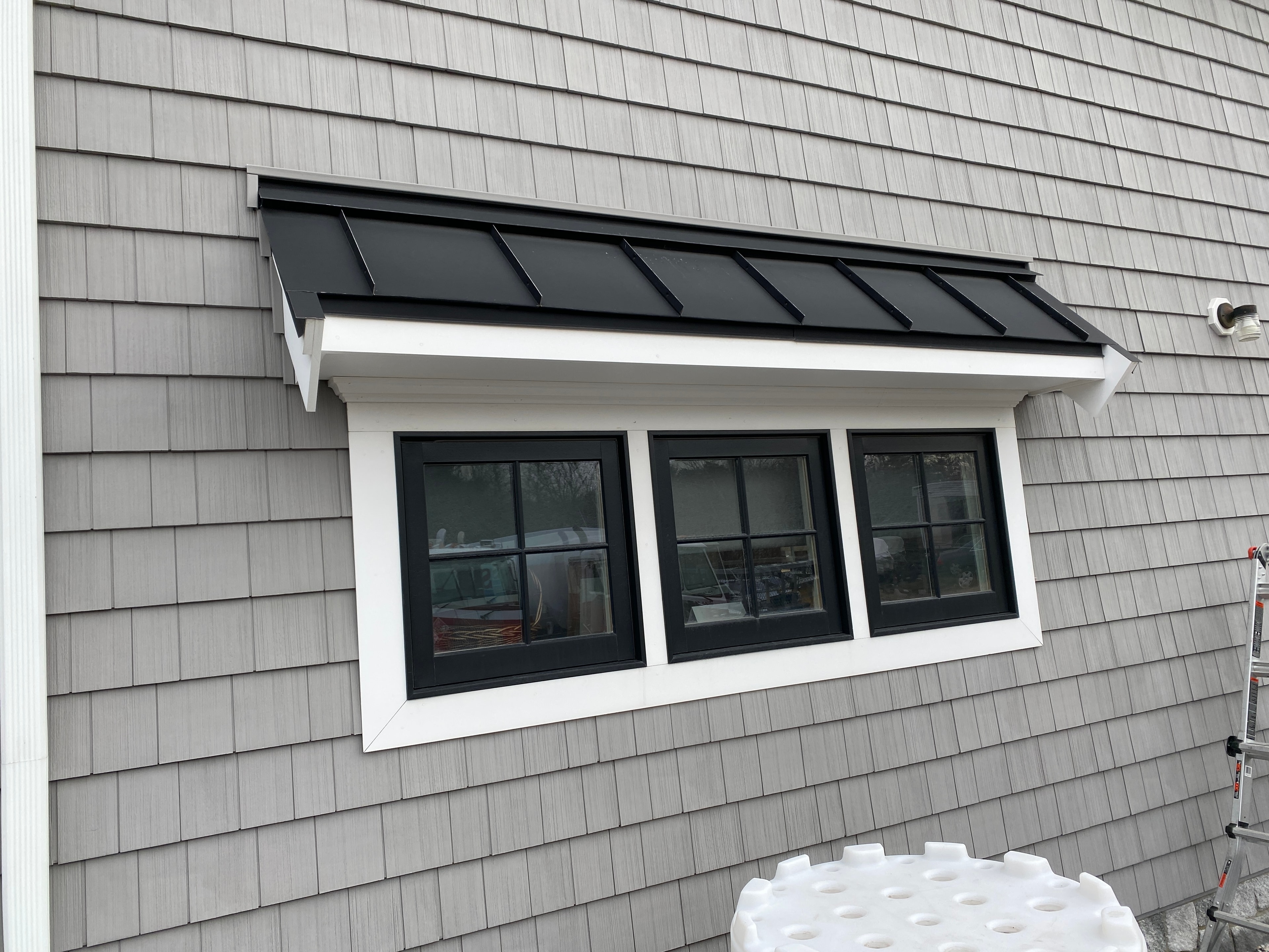 Custom standing seam metal roofing accent over a bay window completed by Boston Js